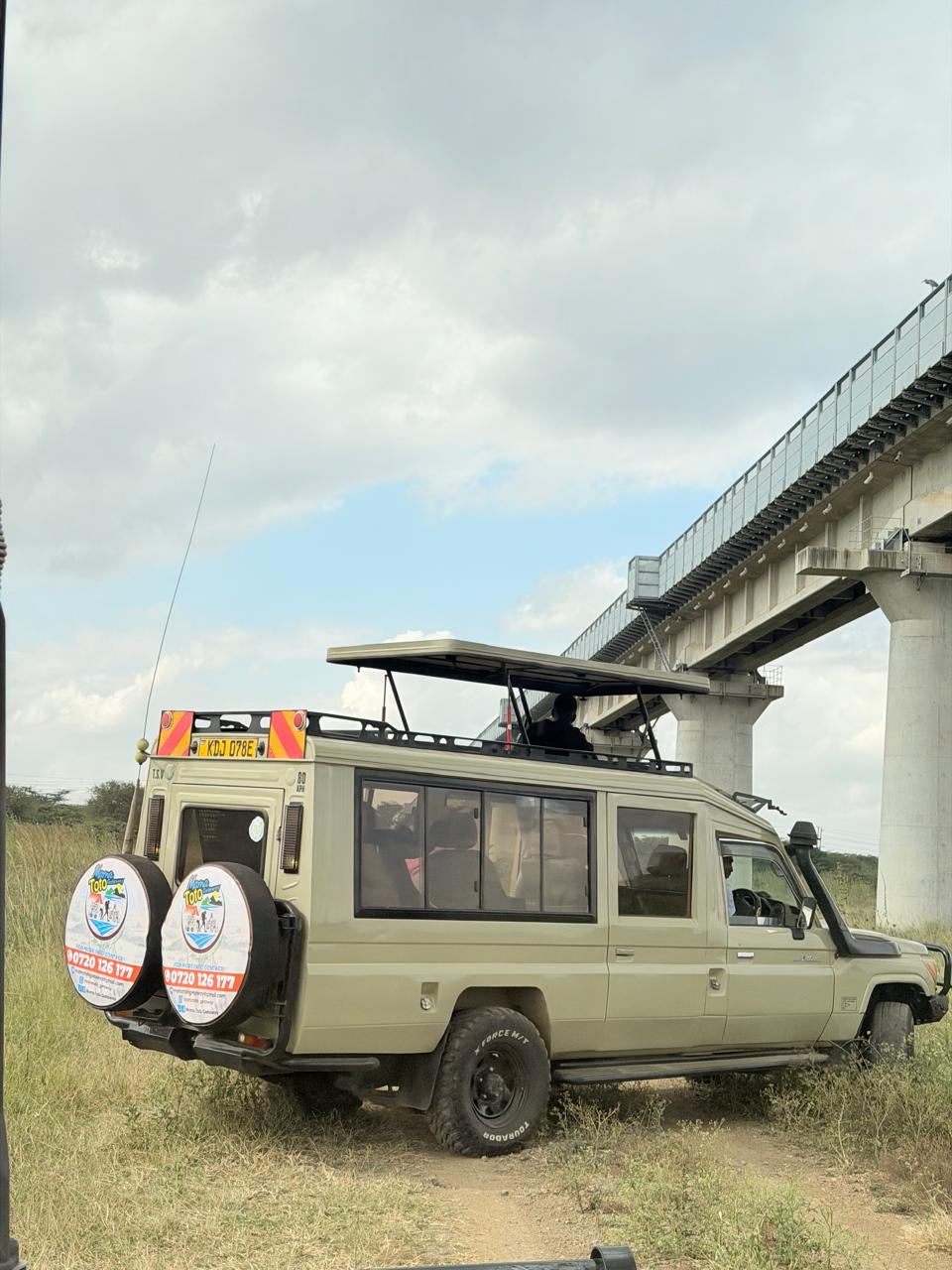 The Mama Toto safari vehicle parked in the grassland with the roof hatch open